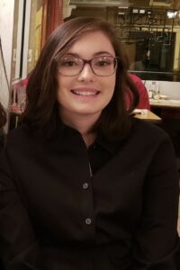 photo of julia cassidy smiling broadly; she has dark hair and wears glasses